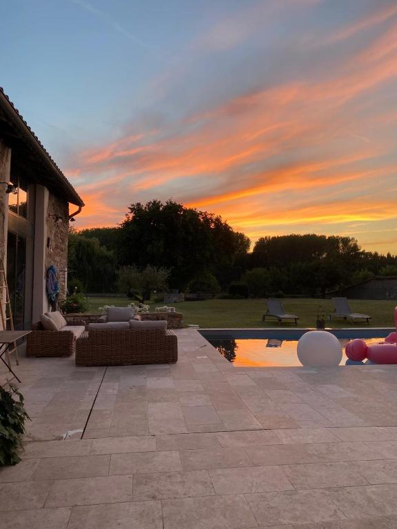 un coucher de soleil sur un patio avec des canapés et une piscine dans l'établissement Notre maison de famille, à Montmerle Sur Saône