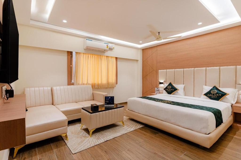 a hotel room with a bed and a couch at Galaxy Royal Suites in Bangalore