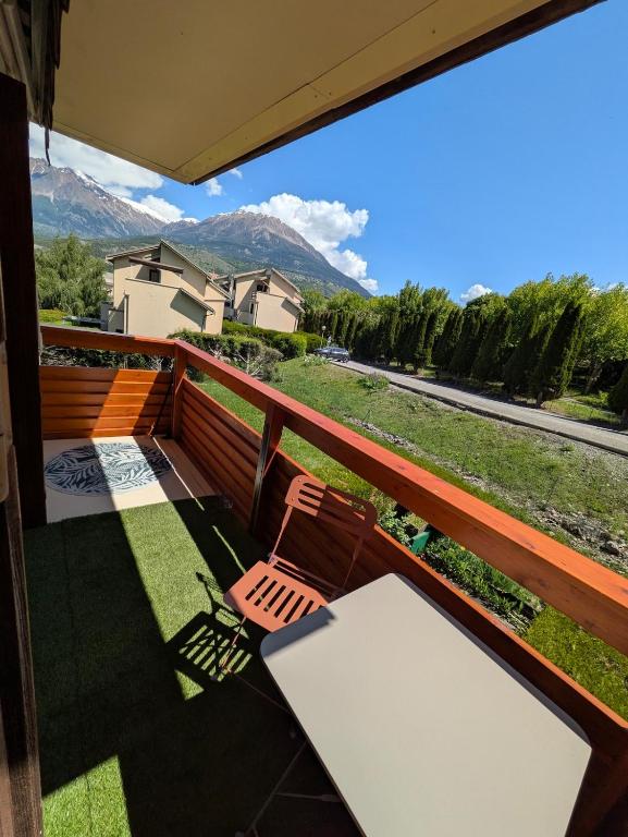 a balcony with a table and chairs and mountains at Face au lac avec parking, proche commerces in Savines