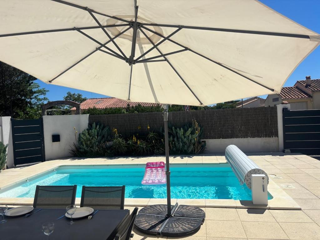 - un parasol blanc à côté de la piscine dans l'établissement Villa contemporaine à 2 pas de la mer avec piscine privée, à Sainte-Marie-la-Mer