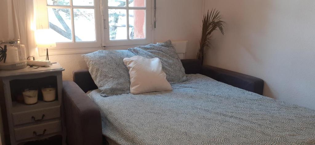 sypialnia z łóżkiem z poduszkami i oknem w obiekcie Superbe Studio accès direct à la plage de Renecros Tout à pied linge de lit, serviettes de bain et ménage de fin de séjour inclus w mieście Bandol