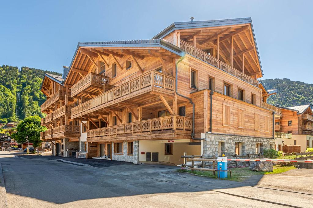 Un grand bâtiment en bois avec balcon se trouve dans une rue. dans l'établissement SmartStay - Super Morzine, à Morzine