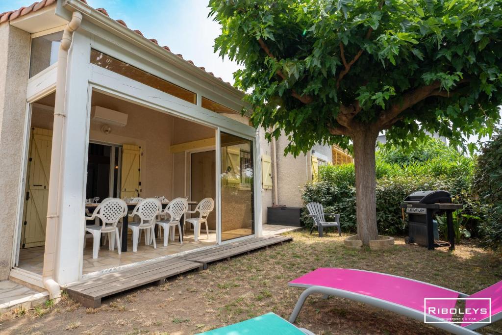 une maison avec une terrasse couverte dotée de chaises et d'un arbre dans l'établissement Villa T4 à 450m de la plage avec climatisation, à Vias