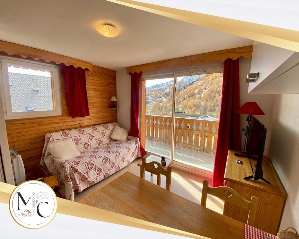 un salon avec un canapé et une grande fenêtre dans l'établissement T2 view, skiing, summer pool Balcons du Soleil, à Allos