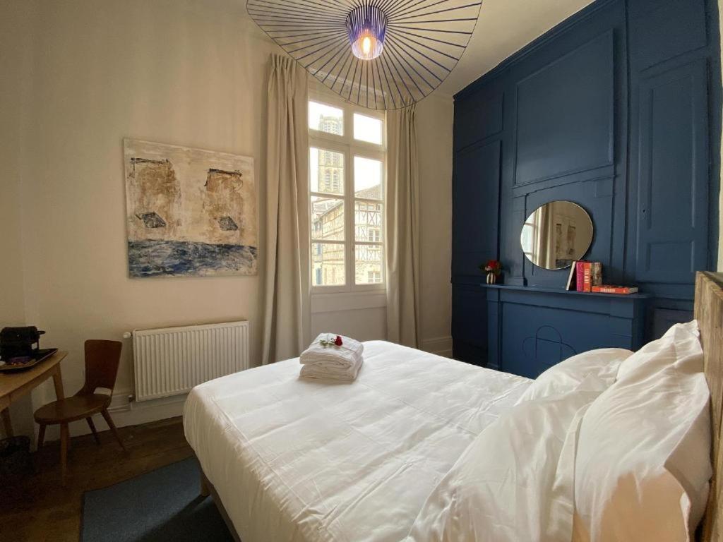 - une chambre bleue avec un lit blanc et un miroir dans l'établissement Les Chambres du Cloître, la Beurrière, à Limoges