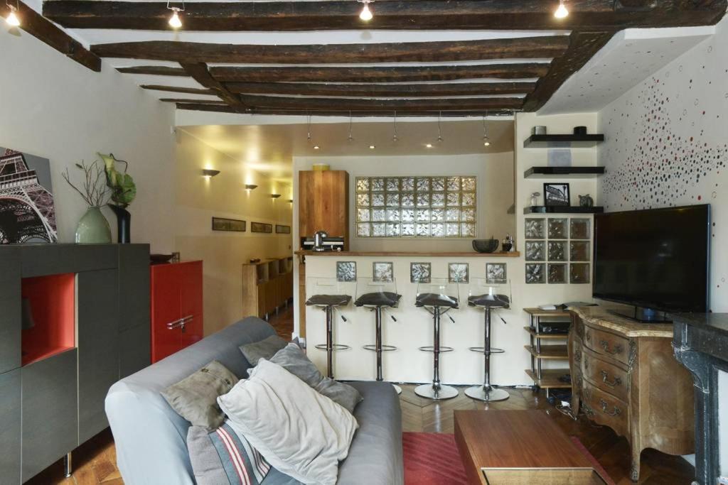 - un salon avec un canapé et quelques tabourets de bar dans l'établissement Le Reflet du Temps, à Paris