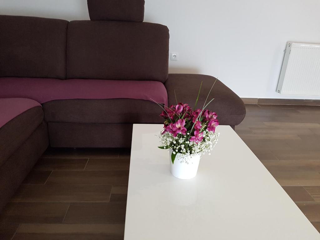 a white coffee table with a vase of flowers on it at Apartments Tereza in Senj