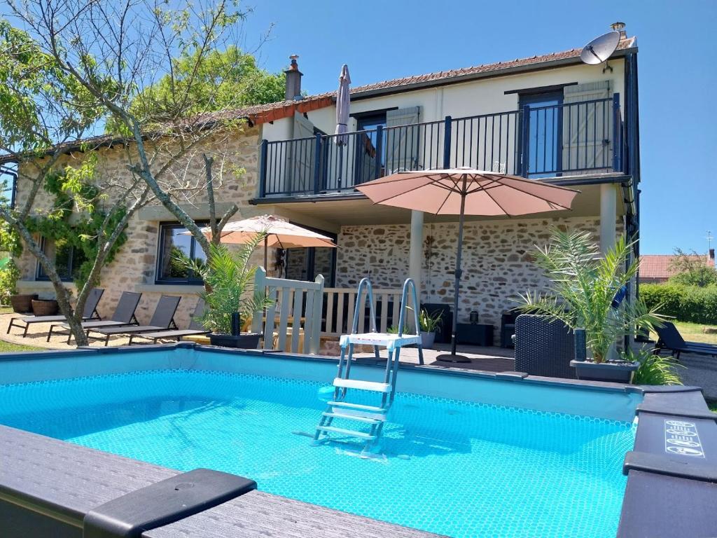 a pool with a chair and an umbrella and a house at Cidre Bois in Saint-Sulpice-le-Dunois