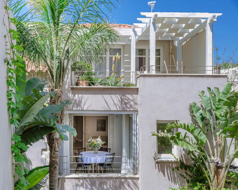 a white house with a table on the balcony at Rimondi Residences Rethymno in Rethymno Town