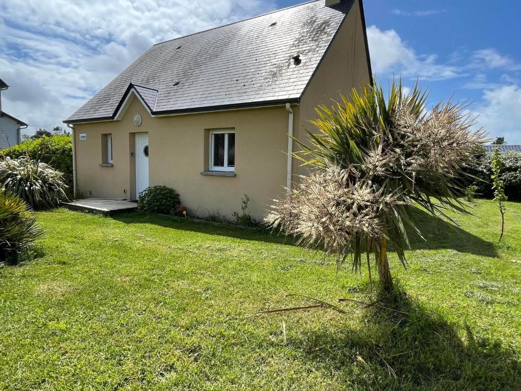 une petite maison dans une cour avec un palmier dans l'établissement Gite du Corps de Garde - Bord de Mer Normandie, à Saint-Germain-sur-Ay