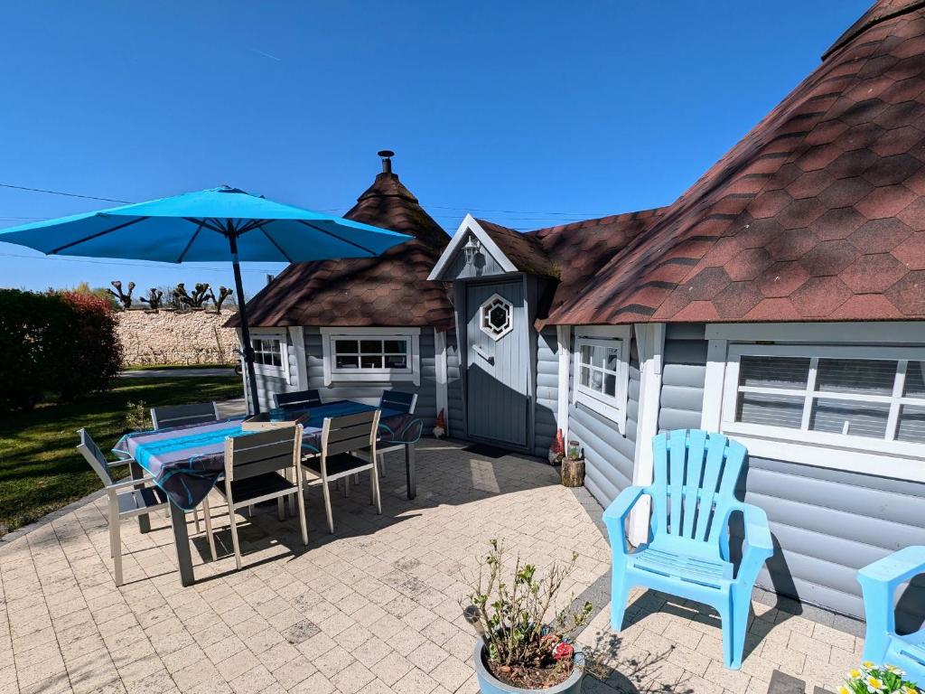 un patio avec une table, des chaises et un parasol dans l'établissement Gîtes en bord de Saône avec hébergements insolites climatisés - FR-1-583-393, à Mantoche