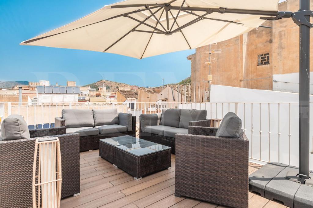 taras z meblami wiklinowymi i parasolem na balkonie w obiekcie Penthouse & private rooftop in the heart of Malaga by REMS w Maladze