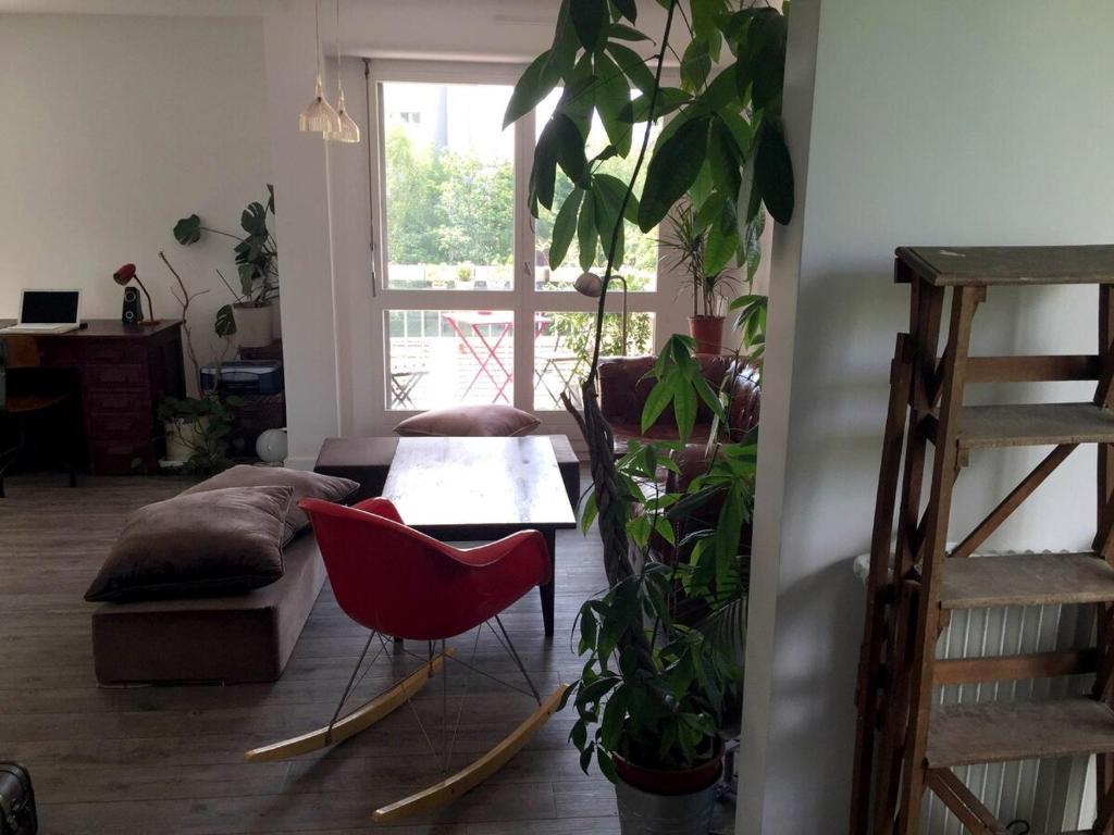 un salon avec une chaise rouge et une table dans l'établissement Beau 4 pièces dans coin de verdure, à Paris