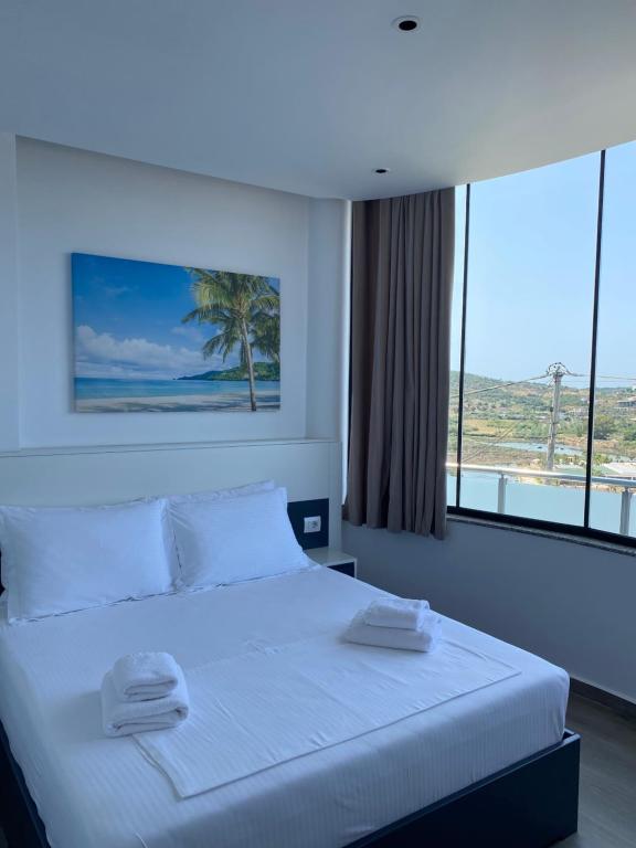 a bedroom with a white bed with a large window at Vila Olserd Shehu in Ksamil