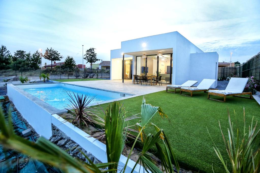 a white house with a swimming pool and a yard at Villa Guadiana Golf 2 in Ayamonte