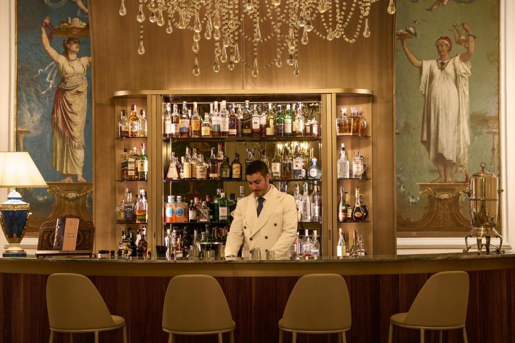 a man in a white suit standing behind a bar at Imperial Hotel Tramontano in Sorrento