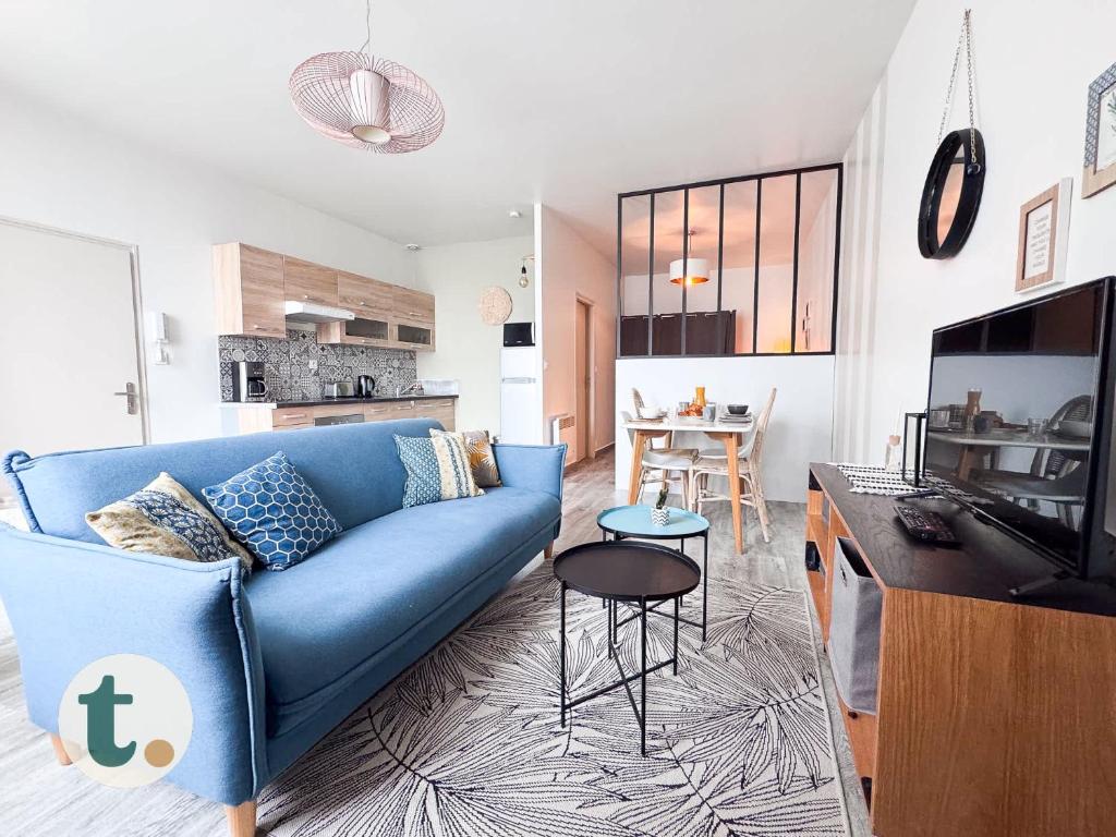 un salon avec un canapé bleu et une cuisine dans l'établissement Tranquiloue - Studio Plein Centre - Puy du Fou 20min, aux Herbiers