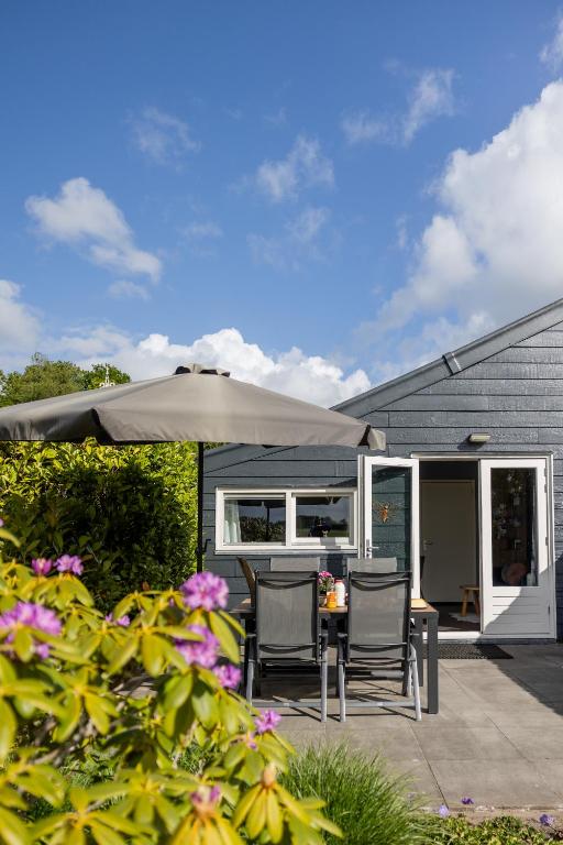 a patio with a table and chairs and an umbrella at Bed & Breakfast de Lindevallei in Oldeberkoop