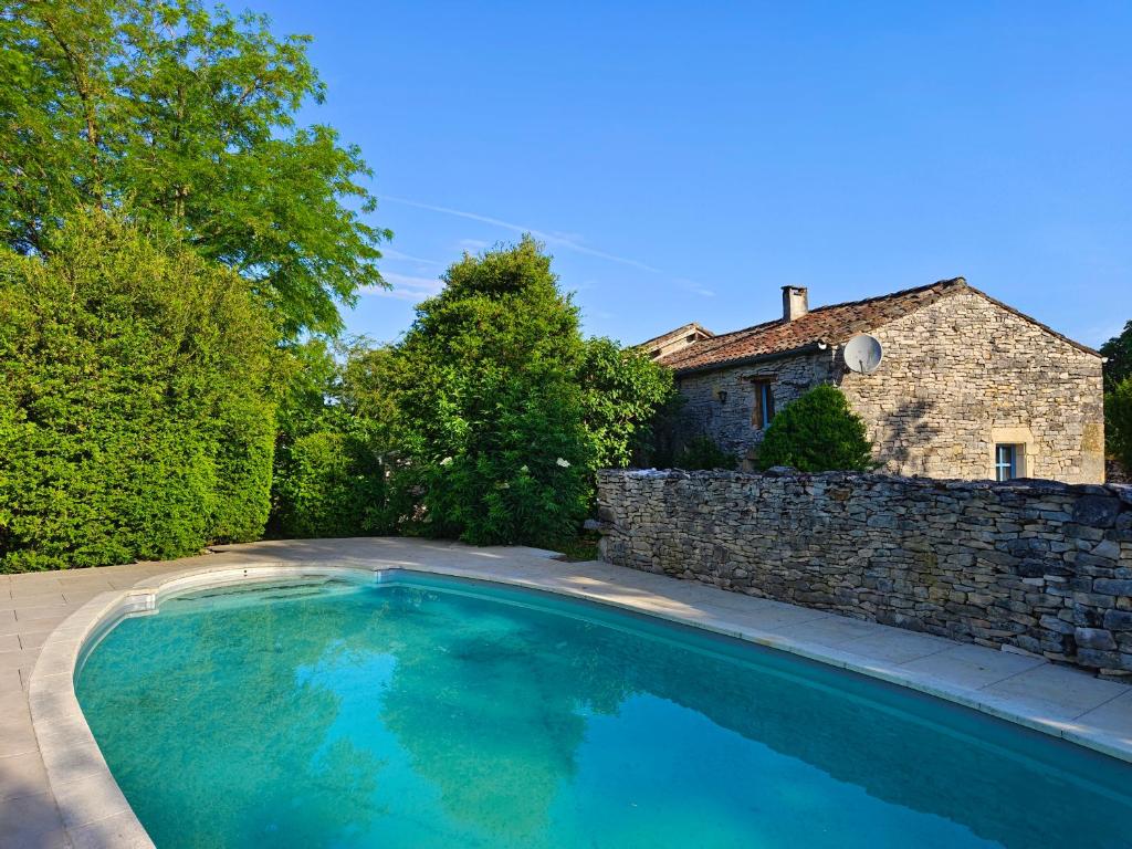- une piscine dans une cour à côté d'un mur en pierre dans l'établissement Gite Valades - avec piscine et vue, à Saint-Antonin