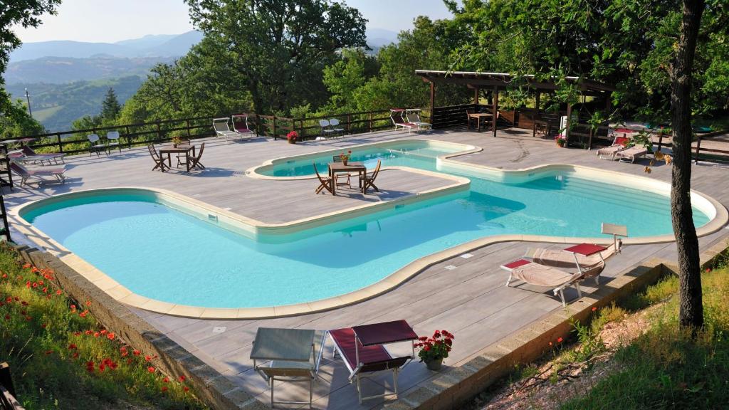 a large swimming pool with a wooden deck and chairs at Lodge Holidays - Casa Tartufo in Radicosa