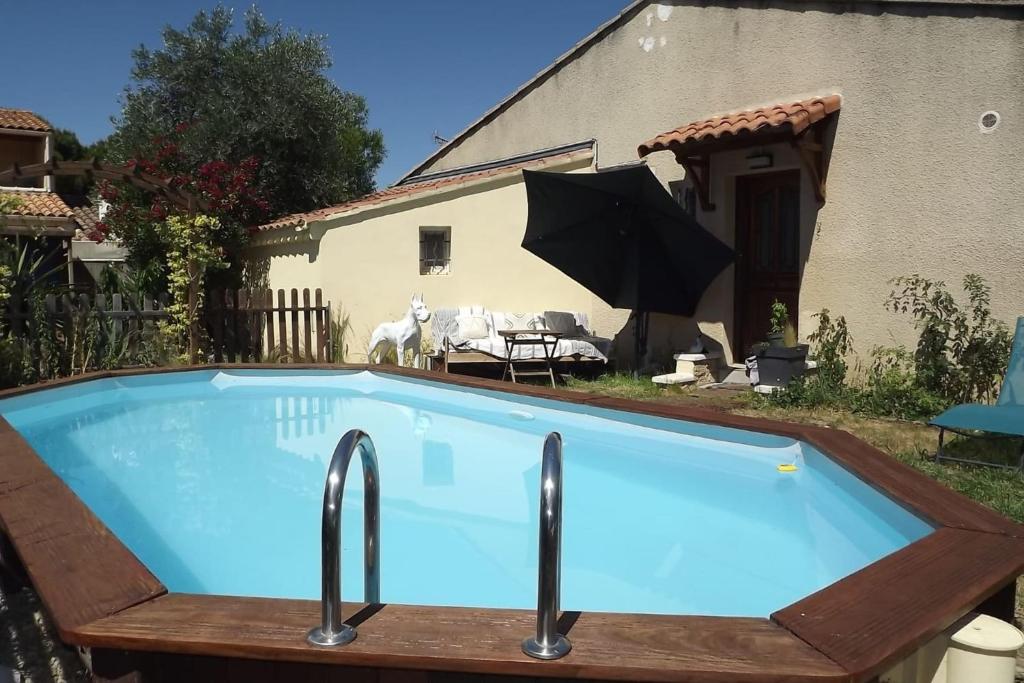- une piscine avec un parasol en face d'une maison dans l'établissement House 3p with private pool in Avignon, à Avignon