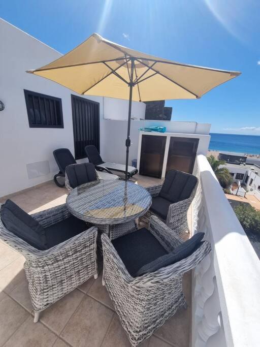a patio with a table and chairs and an umbrella at B16 caleton blanco in Puerto del Carmen