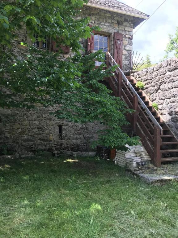 une maison en pierre avec un escalier en bois devant elle dans l'établissement Maison avec balcon à Borne, 70 m², 5 personnes avec jardin, à Mayres