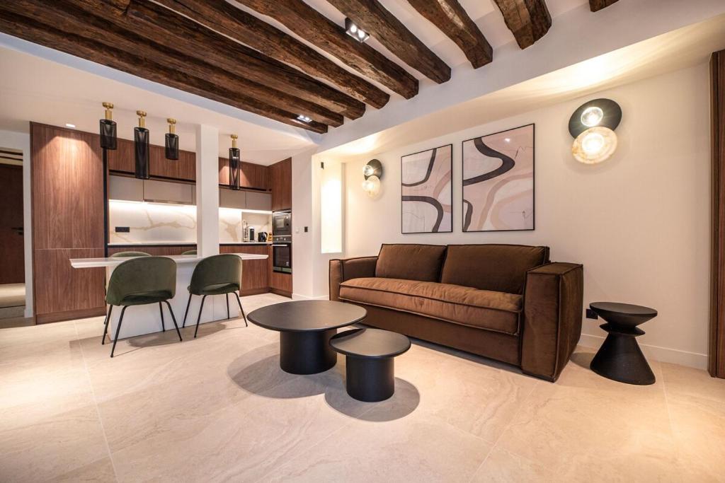 Il comprend un salon avec un canapé et des tables ainsi qu'une cuisine. dans l'établissement Charming Flat in Magnificient Place des Vosges, à Paris
