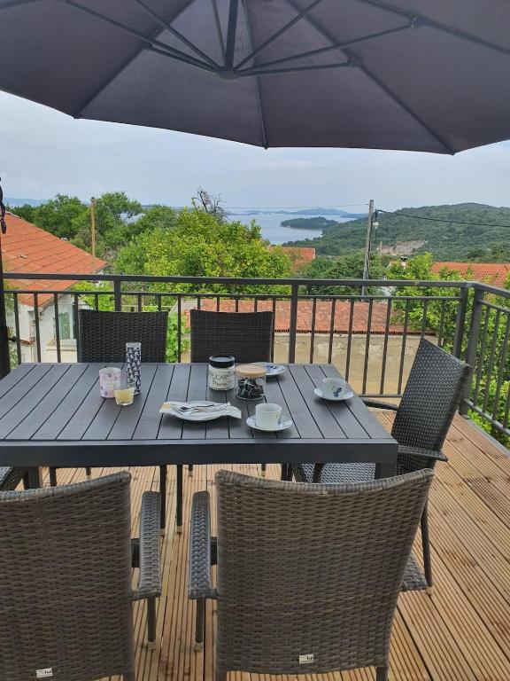 a table with chairs and an umbrella on a deck at Apartment Zaglav in Zaglav