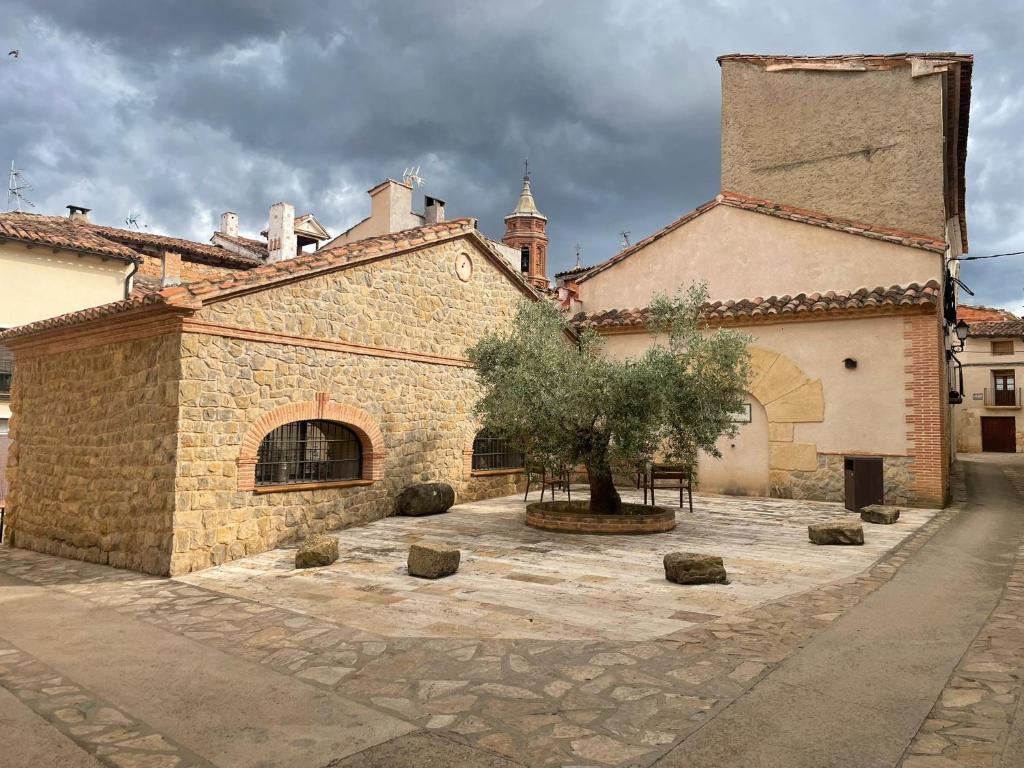 a stone building with a tree in a courtyard at Casa Rural El Ahora in Berge