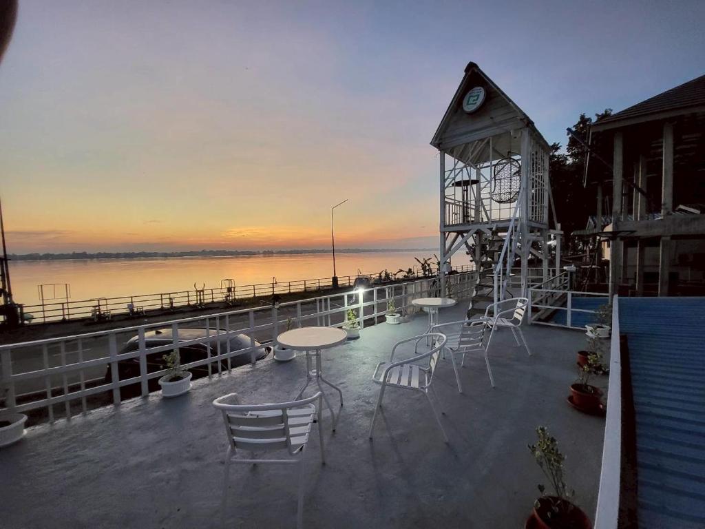 a clock tower sitting on top of a deck with chairs at Aran hostel Spa&Cafe Riverside That Phanom in Amphoe That Phanom