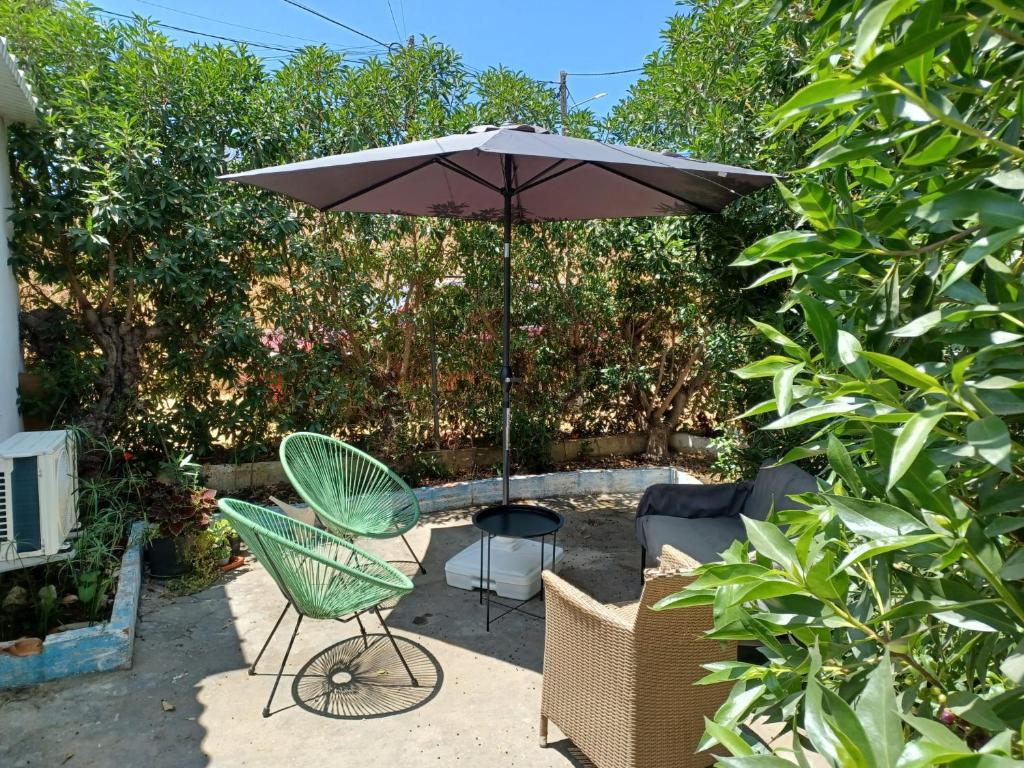 een tafel en stoelen onder een paraplu in een tuin bij Casa de Férias Palmeira in Faro