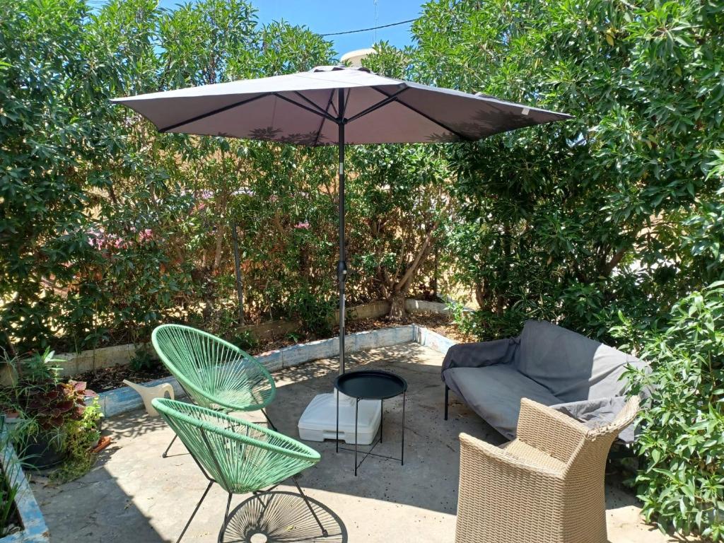eine Terrasse mit einem Tisch, einem Sonnenschirm und Stühlen in der Unterkunft Casa de Férias Palmeira in Faro