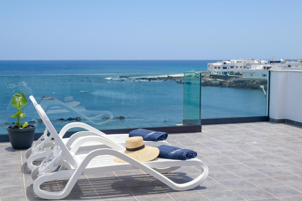 a chair with a straw hat sitting next to a swimming pool at Mariate I Primera línea frente al Mar in Punta Mujeres