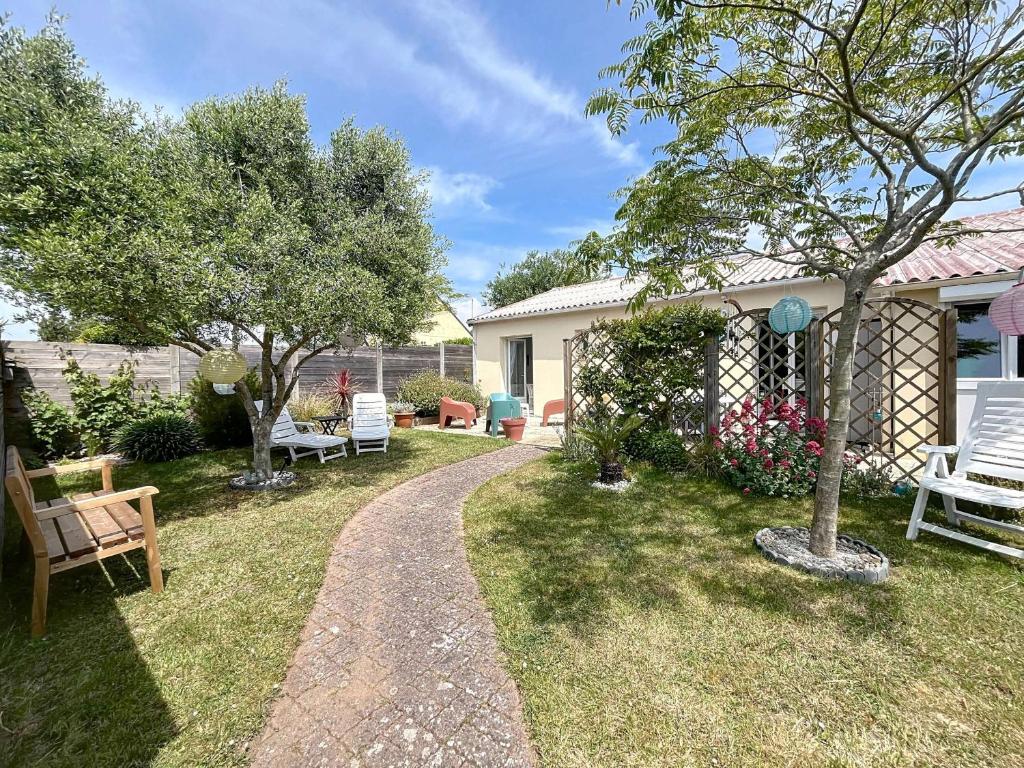 un jardin avec des chaises, un arbre et un chemin dans l'établissement Maison rénovée, à 300m de la plage et proche commerces, avec terrasse et jardin, tout confort - FR-1-361-131, à Saint-Pair-sur-Mer