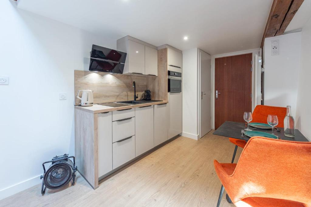 une cuisine avec des armoires blanches et une table et des chaises dans l'établissement Studio TANAGA, à Annecy