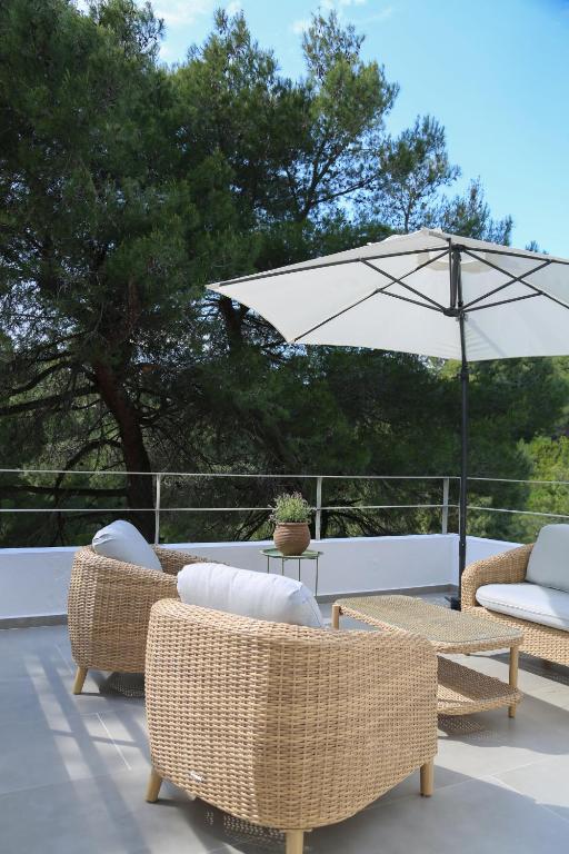 a patio with wicker chairs and an umbrella at Villa Rhodos Skiathos in Skiathos
