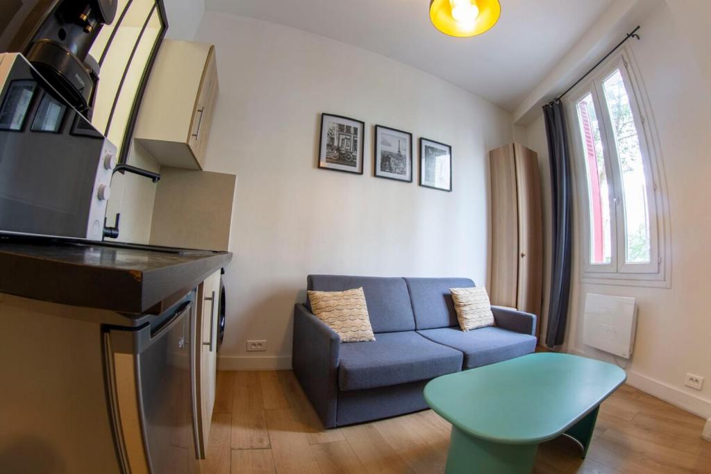 un salon avec un canapé bleu et une cuisine dans l'établissement Agréable appartement dans le 13ème arrondissement, à Paris