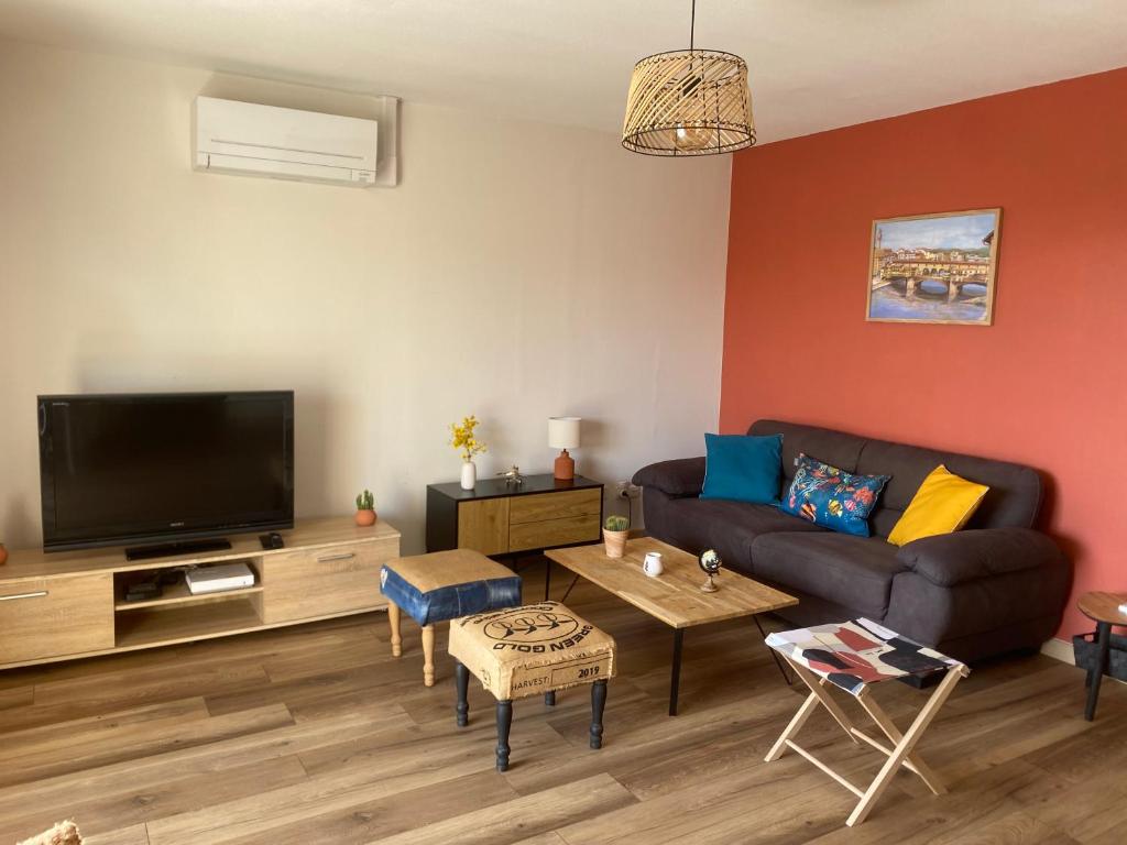 un salon avec un canapé et une télévision à écran plat dans l'établissement La Valériane - Clim, balcon et garage privé, à Montélimar