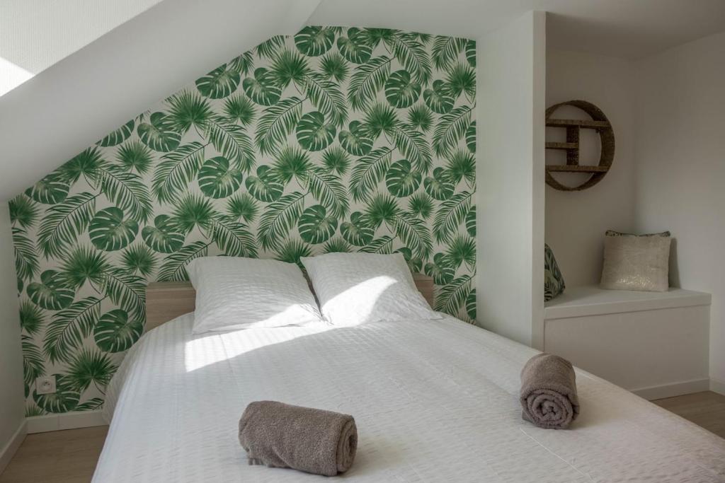 a bedroom with a large white bed with a green wall at Le Naturel, Cocon Calme au Centre-ville in Montargis