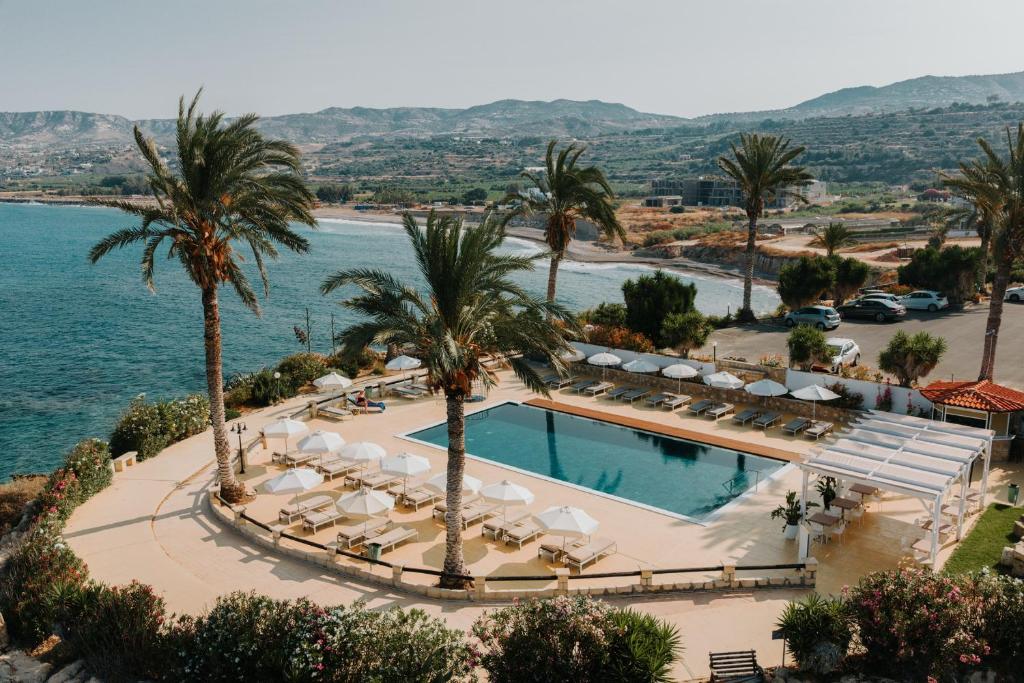 an aerial view of a resort with a pool and palm trees at Vrachia Beach Hotel & Suites - Adults Only in Paphos