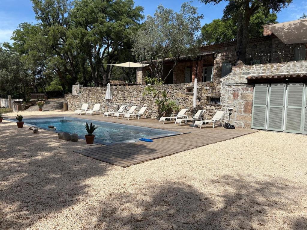 a backyard with a pool and chairs and a building at Bastide de Charme en Pierre avec Piscine dans le Golfe de Saint Tropez in Plan-de-la-Tour