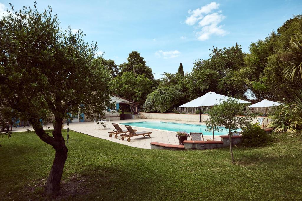 a swimming pool with tables and chairs and a tree at La Ferme de Jeanne in Francescas