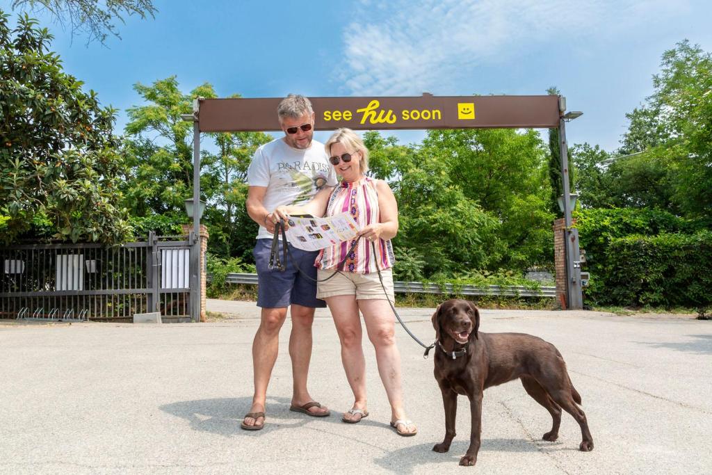 a man and a woman standing next to a dog at hu Firenze Certosa camping in town in Impruneta