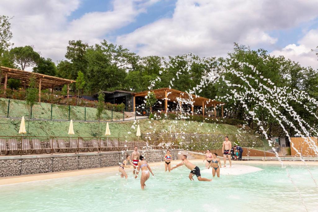 a group of people playing in a fountain in a swimming pool at hu Firenze Certosa camping in town in Impruneta