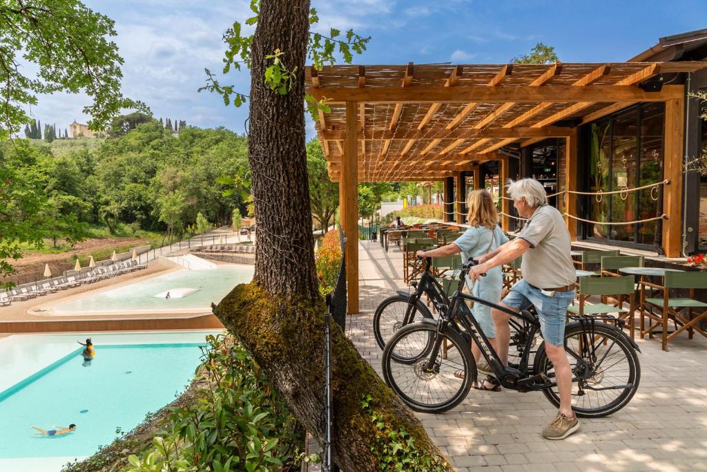 two people on a bike next to a swimming pool at hu Firenze Certosa camping in town in Impruneta