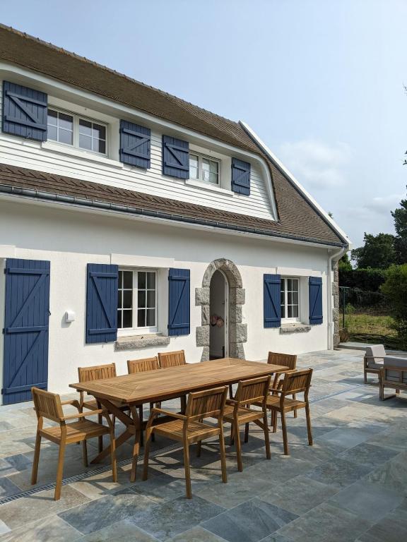 une table en bois et des bancs devant une maison dans l'établissement La Demeure Bleue - Idylliq Collection, à Vénesville