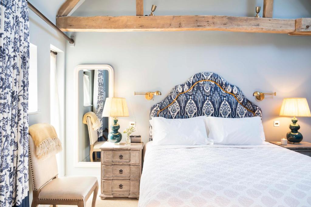 a bedroom with a blue and white bed and a chair at The Wheatsheaf in Chilton Foliat