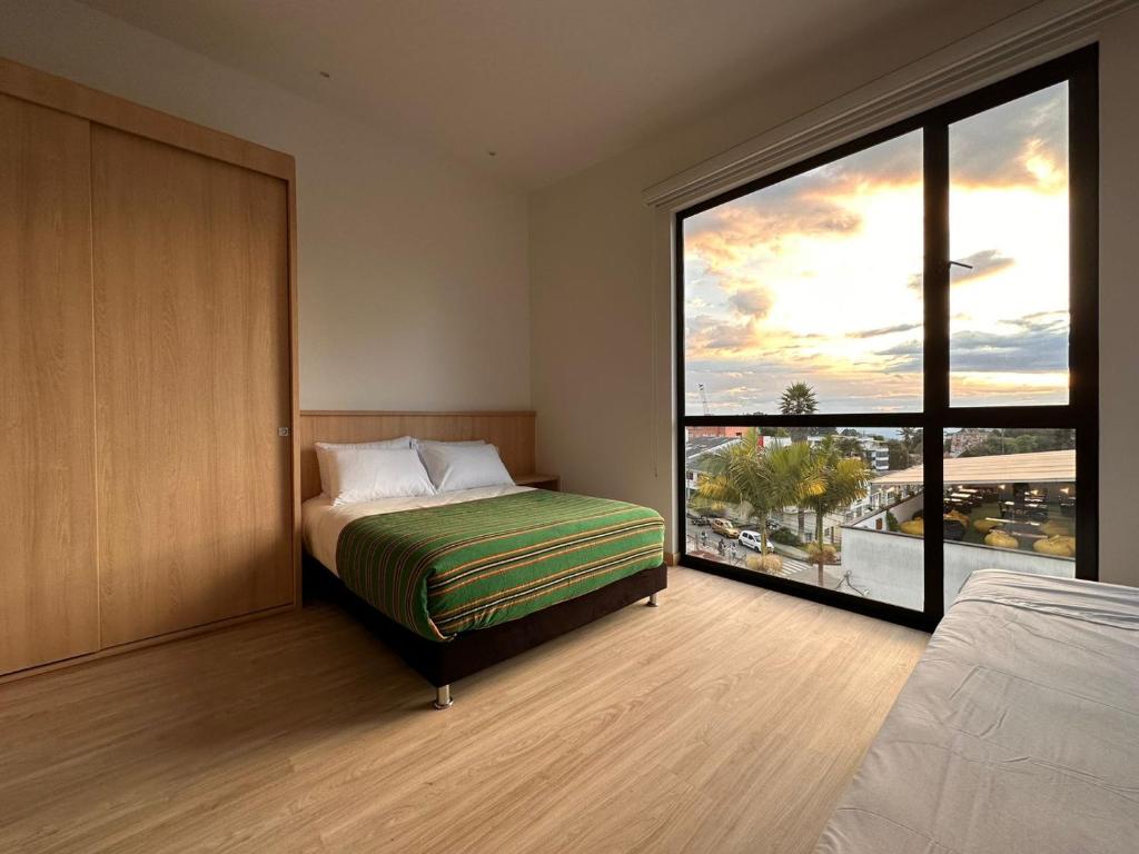 a bedroom with a bed and a large window at Hotel Estar in Manizales