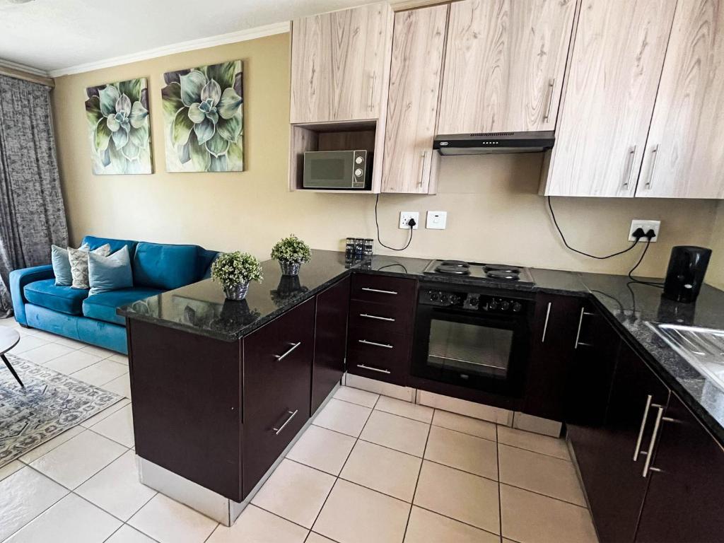 a kitchen with black cabinets and a blue couch at Tshamani self catering in Hazyview